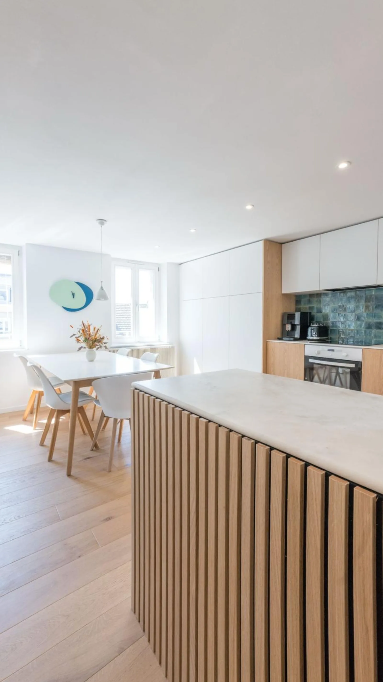 Salle à manger lumineuse avec îlot bois et marbre, parquet chêne clair
